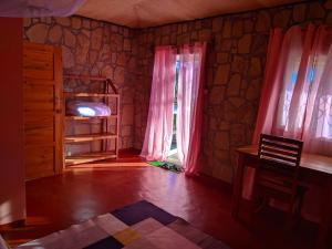 Habitación con cortinas rosas, mesa y ventana en Chambre d'hôte Ristorante Pizzeria Liberta, en Ranohira
