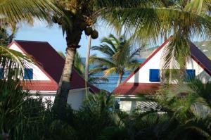 Les Ilets De La Plage في غوستافي: منزل بسقف احمر و ابيض بالنخيل