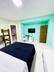 a bedroom with blue walls and a bed and a tv at Pousada Eu Amo Arraial in Arraial do Cabo