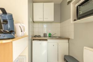 a small kitchen with white cabinets and a sink at Maisonnette cosy proche des 2 Gares et du centre ville Orléans in Orléans +3 photos