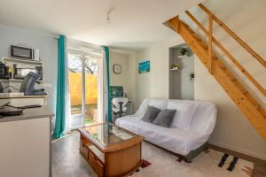 a living room with a white couch and a staircase at Maisonnette cosy proche des 2 Gares et du centre ville Orléans in Orléans