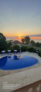 Una gran piscina azul con una puesta de sol al fondo en SEA WOLF Apartman Луксозен апартамент с панорамна гледка към морето климатик с нова напълно оборудвана кухня отделна баня с тоалетна гледка към басейна на 30 м от плажа Паркинг към хотела Навсякъде близо, en Lozenets