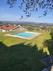 a swimming pool in the middle of a grass field at Casa nos Penedos in Arcos de Valdevez