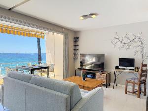 a living room with a couch and a table and a television at La plus belle vue sur mer à Juan les Pins in Antibes