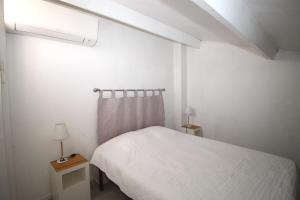 ein weißes Schlafzimmer mit einem Bett und zwei Lampen in der Unterkunft CORAUX - Maisonnette 4 pers avec piscine et parking in Canet-en-Roussillon