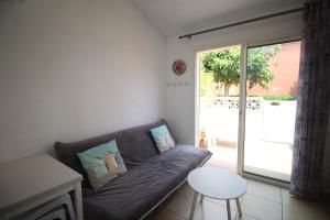 ein Wohnzimmer mit einer Couch und einer Glasschiebetür in der Unterkunft CORAUX - Maisonnette 4 pers avec piscine et parking in Canet-en-Roussillon