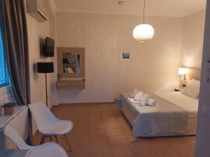 a bedroom with a bed and two chairs and a lamp at Nikolaos Studios Skala in Skala