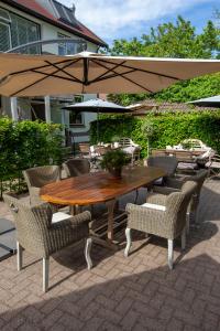 een houten tafel en stoelen met een parasol bij Zenzez Hotel & Lounge in Apeldoorn