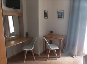 a room with two chairs and a desk and a television at Nikolaos Studios Skala in Skala