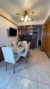 Una mesa de comedor con sillas blancas y un ventilador de techo. en Tranquilo Departamento en Pleno Centro de la Ciudad, en Antofagasta