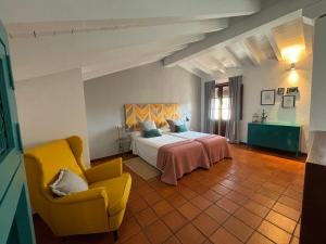 sypialnia z łóżkiem i żółtym krzesłem w obiekcie Alborada Apartamentos Rurales w mieście Hervás