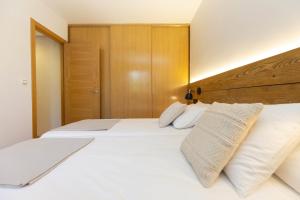 Un dormitorio con dos camas blancas y un cabecero de madera. en El Roble by BeValle, en El Pueyo de Jaca 9 fotos más