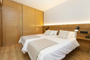 1 cama blanca grande en una habitación con paredes de madera. en El Roble by BeValle, en El Pueyo de Jaca