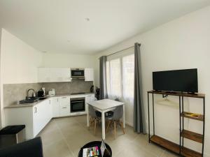 a kitchen with white cabinets and a table and a television at Bordeaux cosy home in Bordeaux +69 photos