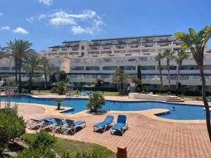 una piscina con sedie a sdraio e un grande edificio di CASA AZUL Mojácar a Mojácar
