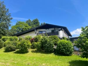 una casa bianca con un tetto nero e alcuni cespugli di Die Landhausvilla in Unterach am Attersee a Unterach am Attersee