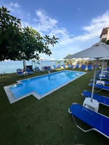 a swimming pool with blue chairs and the ocean at Evita Studios in Xiropigado