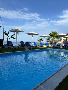 a swimming pool with chairs and umbrellas at Evita Studios in Xiropigado