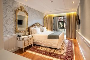 a bedroom with a large bed and a mirror at Pousada Luis XV in Campos do Jordão +92 photos