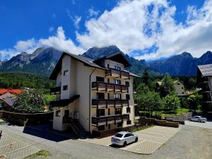 a building with a car parked in a parking lot at Snow Apartament in Buşteni