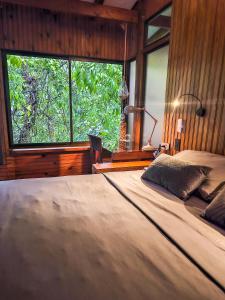 a bedroom with a large bed with a large window at La Uvita Perdida in Uvita