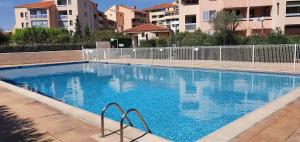 duży niebieski basen z budynkami w tle w obiekcie T2 aux portes du vieux Fréjus et 5 mn de la plage w Fréjus