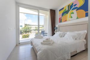 a bedroom with a white bed with a large window at 19 Summer Suites in Santa Cesarea Terme