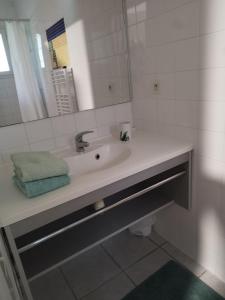 een witte badkamer met een wastafel en een spiegel bij Maisonnette drômoise in Châteauneuf-sur-Isère