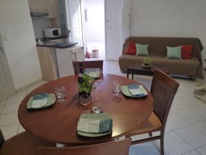 een houten tafel met borden en glazen en een bank bij Maisonnette drômoise in Châteauneuf-sur-Isère