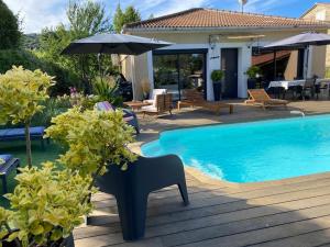 a pool with chairs and an umbrella next to a house at Villa 2 chambres piscine in Cauro