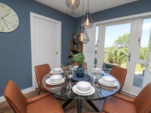 Un comedor con una mesa y sillas y un reloj. en Cysgod Y Garn, en Newport