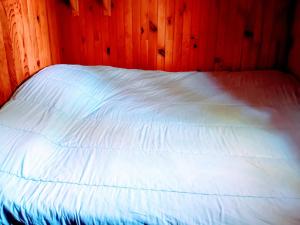 a bedroom with a white bed with wooden walls at Chalet dans camping à Camon in Camon +18 photos