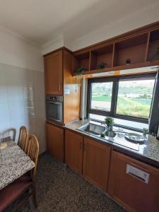 a kitchen with wooden cabinets and a sink and a window at Mountain View Beach House in Costa da Caparica