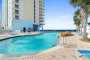 a swimming pool with chairs and palm trees at a resort at Majestic Beach Resort Tower I by Panhandle Getaways in Panama City Beach