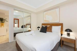 a bedroom with a large white bed and a mirror at 1BR Stylish Suite on Hay St in Perth +20 photos
