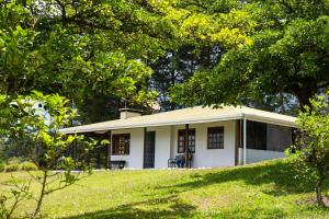 a small white house in a field with trees at Country house, Cozy Fireplace and an amazing view in Cartago