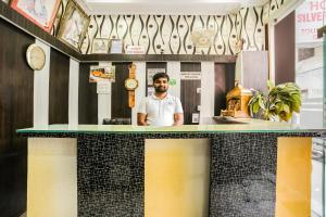 a man standing behind a counter in a restaurant at Hotel Silver Palace in New Delhi