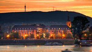 a large building with a clock tower next to a body of water at Verdi Budapest Aquincum in Budapest