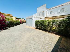a brick driveway in front of a white building at Villa Bosque Novo Sancti petri Grupo AC Gestión in Chiclana de la Frontera