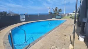 a large blue swimming pool next to a building at SEA FACING modern 3-bedroom apartment, Umdloti in Umdloti