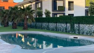 a swimming pool in front of a building with palm trees at Apartamento con jardin Long Beach Loredo in Loredo