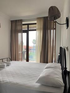 a bedroom with a white bed with a large window at Gonio Beach Apartment in Batumi +6 photos