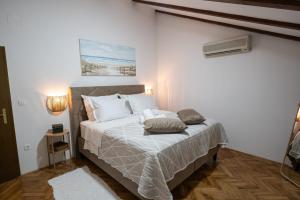 a bedroom with a bed with white sheets and pillows at Holiday home Coastal Soul in Mali Ston in Mali Ston