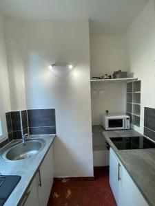a small kitchen with a sink and a microwave at Appartement de charme près du Stade de France in Saint-Denis