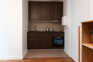 een keuken met bruine kasten en een fornuis bij Joli studio proche de paris -pantin in Pantin +15 foto's