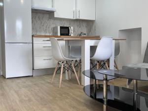 a kitchen with white chairs and a table and a refrigerator at Céntrico apartamento muralla 1 in Lugo