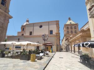 una calle de la ciudad con mesas, sombrillas y edificios en Casa Bijou, en Marsala