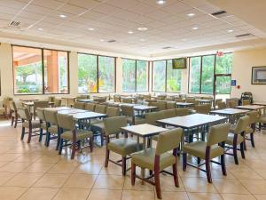a dining room with tables and chairs and windows at Hotel Monreale Express & Studios IDrive District in Orlando