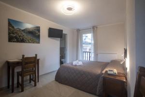 a bedroom with a bed and a desk and a window at Albergo Miniere in Traversella