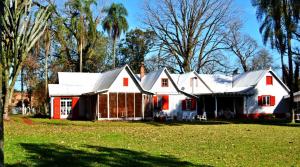 a large white house with red shutters on a yard at Estancia Las Mercedes in Eldorado